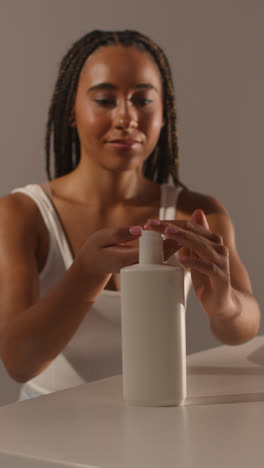 Studio-Skincare-Beauty-Shot-Of-Woman-Dispensing-Moisturiser-From-Bottle-Into-Hand